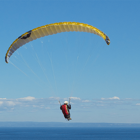 vertical-shot-person-paragliding-sea-sunlight